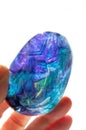 Fluorite crystal hand held in sunlight with purple, blue and turquoise colors