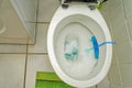 flushing water toilet wc seat with foam with blue scented stones as scent rinser and opened seat white tiles floor