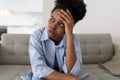 Flustered African American woman is very nervous sighing and touching face with hands sits on sofa Royalty Free Stock Photo