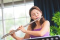 Flute classical instrument profestional player playing song. A young and elegant Asian woman plays the flute