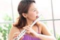 Flute classical instrument profestional player playing song. A young and elegant Asian woman plays the flute