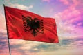 Fluttering Albania flag on colorful cloudy sky background. Prosperity concept