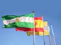 Fluttering flags of Andalusia, Spain, Isla Cristina and Blue Flag. Royalty Free Stock Photo