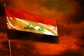 Fluttering Iraq flag on crimson red sky with smoke pillars background. Troubles concept