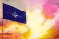 Fluttering NATO flag in top left corner mockup with the space for your text on beautiful colorful sunset or sunrise background