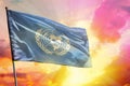 Fluttering United Nations flag on beautiful colorful sunset or sunrise background. Success concept