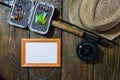 Fly box with flies and a hat on a wooden table. Royalty Free Stock Photo