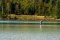 Fly fisherman stands in a waders in a lonely mountain lake while casting a fishing rod in the clear lonely lake in Bavaria in the