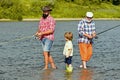 Fly fisherman using fly fishing rod in river. Family generation and people concept. Grandson with father and grandfather Royalty Free Stock Photo