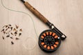 Fly fishing reel, rod, and flies on a light wood background Royalty Free Stock Photo