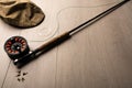 Fly fishing reel, rod, and flies on a light wood background