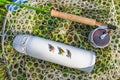 Fly fishing tackle. Flies on thermo water bottle, rod, reel in fishing landing net Royalty Free Stock Photo