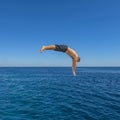 Fly after jump. Man jumping in blue sea water for dive. Summer fun lifestyle