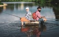 Fly rod and reel with a brown trout from a stream. Happy father and son together fishing in summer day under beautiful Royalty Free Stock Photo