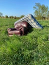 Fly tipped furniture in a grassy field. Portrait view
