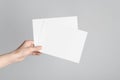 A5 Flyer / Invitation Mock-Up - Male hands holding blank flyers on a gray background Royalty Free Stock Photo