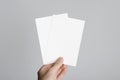 A6 Flyer / Postcard / Invitation Mock-Up - Male hands holding blank flyers on a gray background Royalty Free Stock Photo