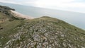 Flying above beautiful rocky sea shore with green meadow. Action. Aerial view of stone and sand beach and green field. Royalty Free Stock Photo