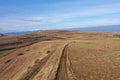 Flying above a countryside dirt road and meadow, aerial view