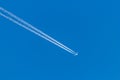 Flying airplane on a journey through the blue sky with a long white smoking exhaust plume and jetwash show international transport Royalty Free Stock Photo