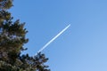 Flying airplane on a journey through the blue sky with a long white smoking exhaust plume and jetwash show international transport