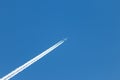 Flying airplane on a journey through the blue sky with a long white smoking exhaust plume and jetwash show international transport Royalty Free Stock Photo