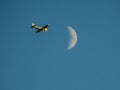 Flying airplane and lit moon in blue sky Royalty Free Stock Photo