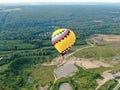 Flying in balloons over a green field and forest against the background of a blue sky at sunset in summer. Drone shot Royalty Free Stock Photo