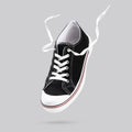 Flying black sneakers isolated on gray background. Fashionable stylish sports casual shoes. Creative minimalistic layout with