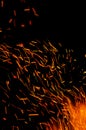 Flying burning red sparks on a black background. Fiery orange glowing particles flying away in night sky. Abstract Royalty Free Stock Photo