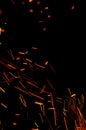 Flying burning red sparks on a black background. Fiery glowing particles flying away in night sky. Abstract background