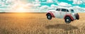 Flying car soars into the sky. Retro automobile hovers in the air above a golden wheat field on the background of blue sky. Royalty Free Stock Photo