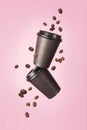 Flying coffee from a paper cups with flying coffee beans on a pink background. Coffee concept. Mock up. Empty polystyrene coffee
