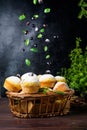 Flying cupcakes with mint leaves and black currants in powdered sugar on a black background, a wooden basket with cupcakes and Royalty Free Stock Photo