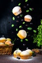 Flying cupcakes with mint leaves and black currants in powdered sugar on a black background, a wooden basket with cupcakes and Royalty Free Stock Photo