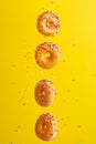 Flying donuts. Many donuts with colored caramel with sprinkles on a yellow background. Vertical photo. Freezing in motion