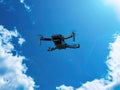 Flying drone against a blue sky with white clouds. Royalty Free Stock Photo