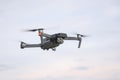 A flying drone against a cloudy sky in cloudy weather takes pictures of the surface of the earth