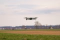 A flying drone against a cloudy sky in cloudy weather takes pictures of the surface of the earth