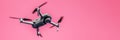 Flying Drone With Camera On Pink Background With Copy Space. Airborne Quadcopter. Also Known As A Drone Or UAV.