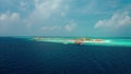 Flying a drone over a coral reef to a luxure resort island in the Maldives