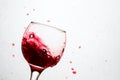 Flying drops of red wine around a tilted glass Royalty Free Stock Photo