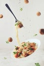 Flying food. Levitation of pasta fettuccine with meatballs, tomato sauce, basil on white background