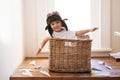 Flying, fun and child with paper plane, fantasy, and imagination playing in basket in home. Adventure, little pilot and Royalty Free Stock Photo
