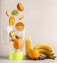Flying ingredients for making smoothies from oranges, kiwi and bananas, vegetarian healthy food, fruit lined around a green blende