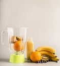 Flying ingredients for making smoothies from oranges, kiwi and bananas, vegetarian healthy food, fruit lined around a green blende