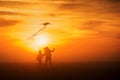 Flying a kite. Girl and boy fly a kite in the endless field. Bright sunset. Silhouettes of people against the sky