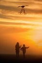 Flying a kite. Girl and boy fly a kite in the endless field. Bright sunset. Silhouettes of people against the sky Royalty Free Stock Photo