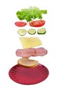 Flying layers of sandwich with ham, cheese and vegetables over the red plate isolated on white background Royalty Free Stock Photo