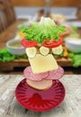 Flying layers of sandwich, ham, cheese, vegetables and red plate over the wooden table. Breakfast food concept Royalty Free Stock Photo